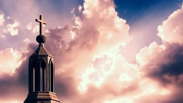 Cruz sobre el campanario de una iglesia con cielo nublado